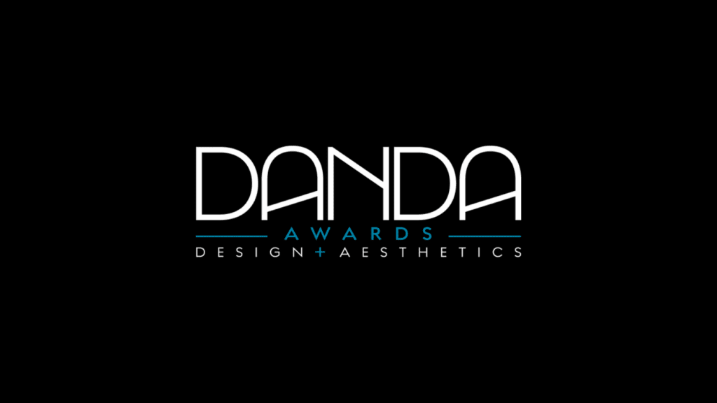 Logo for Danda Awards on a black background. Bold white text says "DANDA," with "AWARDS" in smaller blue text below. "DESIGN+AESTHETICS" in white underlines it.